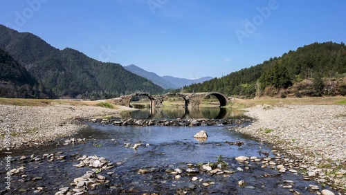 Wallpaper Mural Time-lapse of the historic three-arch stone bridge over a flowing stream in Wuyuan County, Jiangxi Province, China. Torontodigital.ca