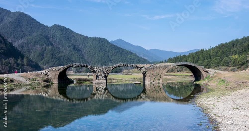 Wallpaper Mural Close-up time-lapse of the ancient three-arch stone bridge with blue sky, clear water, and mirror-like reflections in spring, Wuyuan county, Jiangxi province, China. Torontodigital.ca