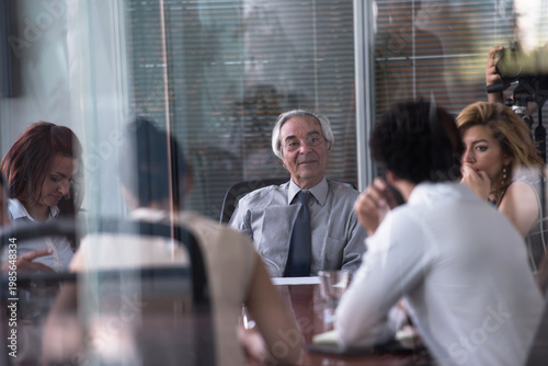 Bild auf Leinwand Senior executive leading a business meeting in a modern glass boardroom with att
