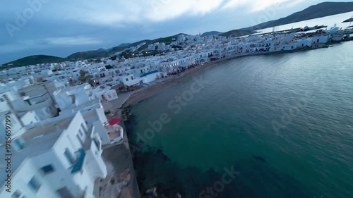 Cinematic FPV drone flight over Naousa village on Paros island during sunset, featuring warm evening light, coastal harbor and Easter celebrations with festive atmosphere