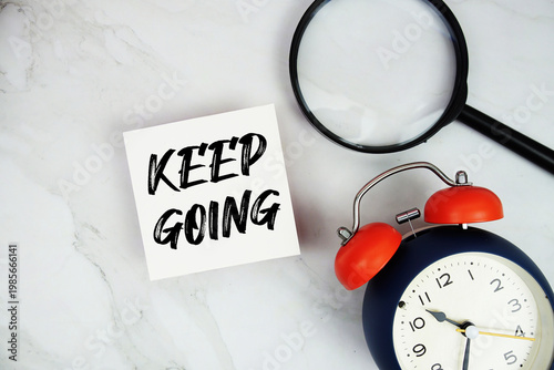 Photography Keep Going text with sticky note and alarm clock flat lay on marble background