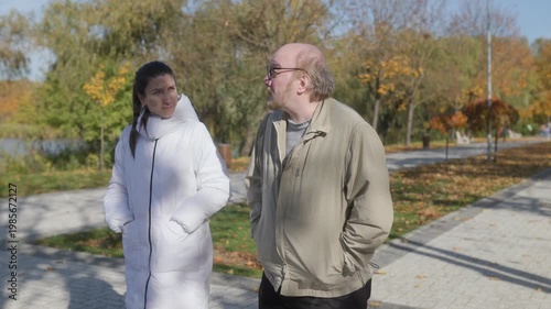 Elderly man walks with caregiver in park, concept of elderly support