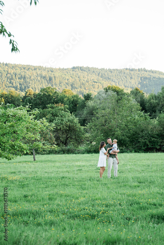 Happy young family with little son playing with kite in field. Healthy childhood.