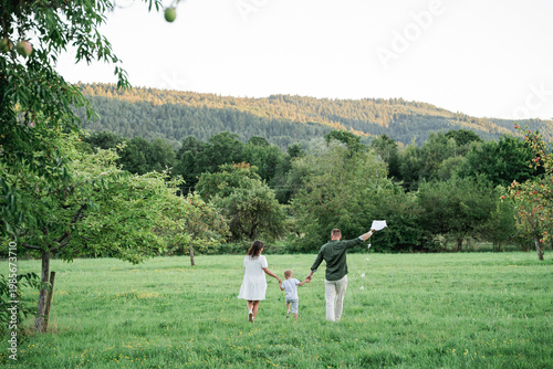 Happy young family with little son playing with kite in field. Healthy childhood.