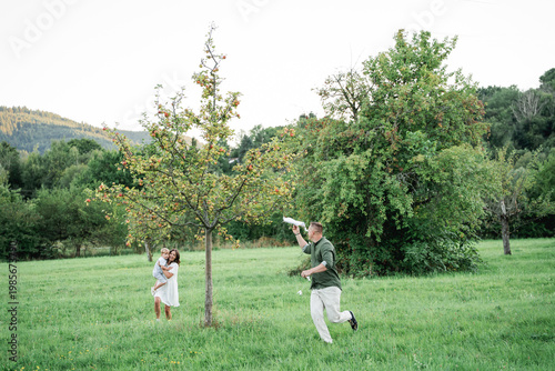Happy young family with little son playing with kite in field. Healthy childhood.