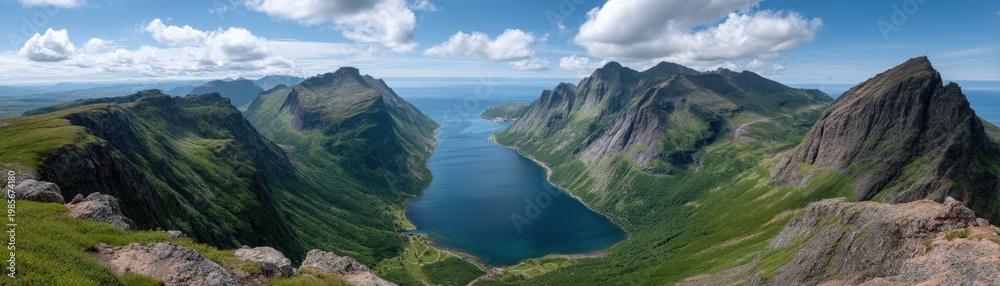 Fototapeta premium Panoramic view of a dramatic fjord valley with steep green mountains and calm blue water under a bright summer sky