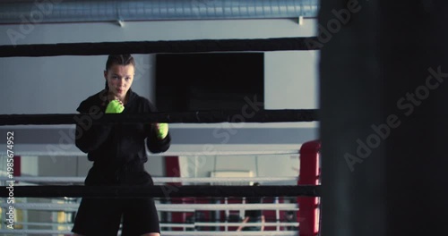 A focused teen girl boxer trains hard in shadow fighting, using every movement to build endurance, technique, and fight readiness in the gym. Slow motion 4k footage.