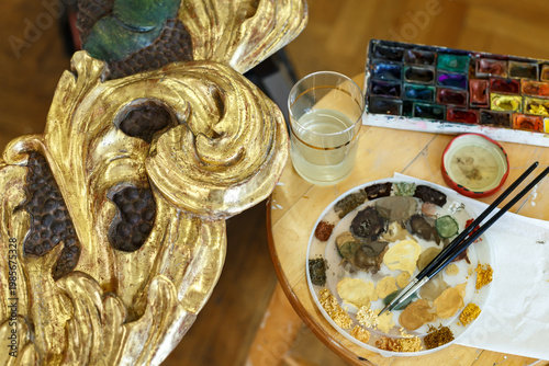 Artist Prepares Paint and Tools on Wooden Table in Studio While Creating Art Project in Afternoon Light