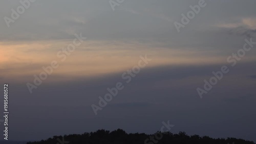 Bright Sky Band Over Dark Clouds and Tree Silhouettes on Horizon.