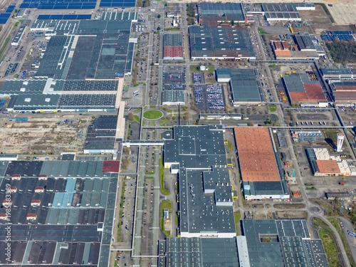 Aerial view of sprawling industrial complex with geometric patterns and a mix of grey and orange roofs under the vast sky, Sausheim, Grand Est, France.