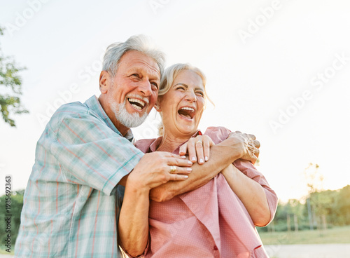 Foto Happy active senior couple having fun talking and hugging in park outdoors