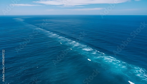 Aerial view of deep blue ocean with a long diagonal wave line cutting through calm water, creating a striking minimalist seascape.