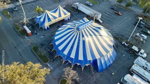Aerial view of the vibrant blue and white striped circus tents standing boldly amidst the stark asphalt of the parking lot, St. Augustine, Florida, United States.