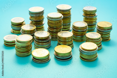 Stacks of coins next to each other, on light blue surface. Amount of money and wealth.