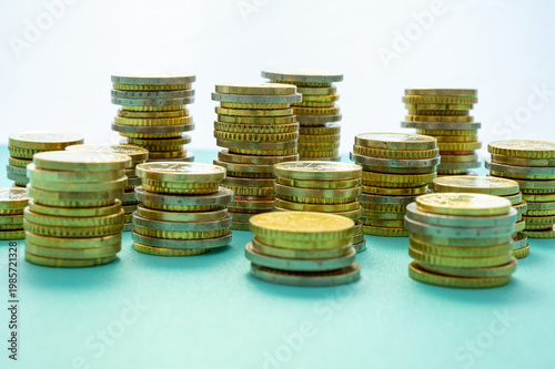 Stacks of coins next to each other, on light blue surface. Amount of money and wealth.