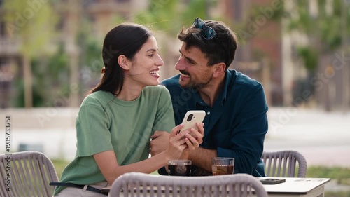 Video of tender couple talking and laughing while having a drink on a terrace in the city
