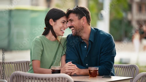 Video of tender couple talking and laughing while having a drink on a terrace in the city