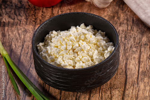 Valokuva Fresh granulated cottage cheese in a black bowl on a rustic wooden table with gr