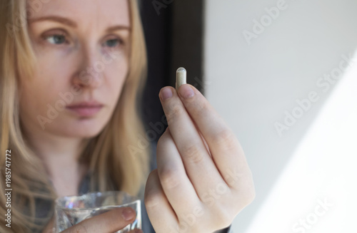 фотографія Woman taking iron supplement capsule with glass of water