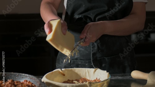 Slow Motion of a Chef Grating Fresh Cheese for Homemade Lasagna in a Modern Kitchen