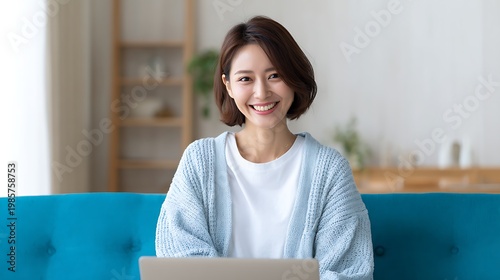 Smiling Japanese Woman Using Laptop on a Sofa / ソファでパソコンを使う笑顔の日本人女性