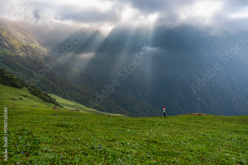 Canvas Print A serene landscape of green hills and mountains with sunbeams shining through cl