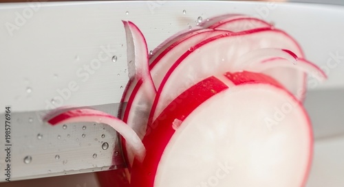Close-up of a Radish Being Sliced on a White Surface.