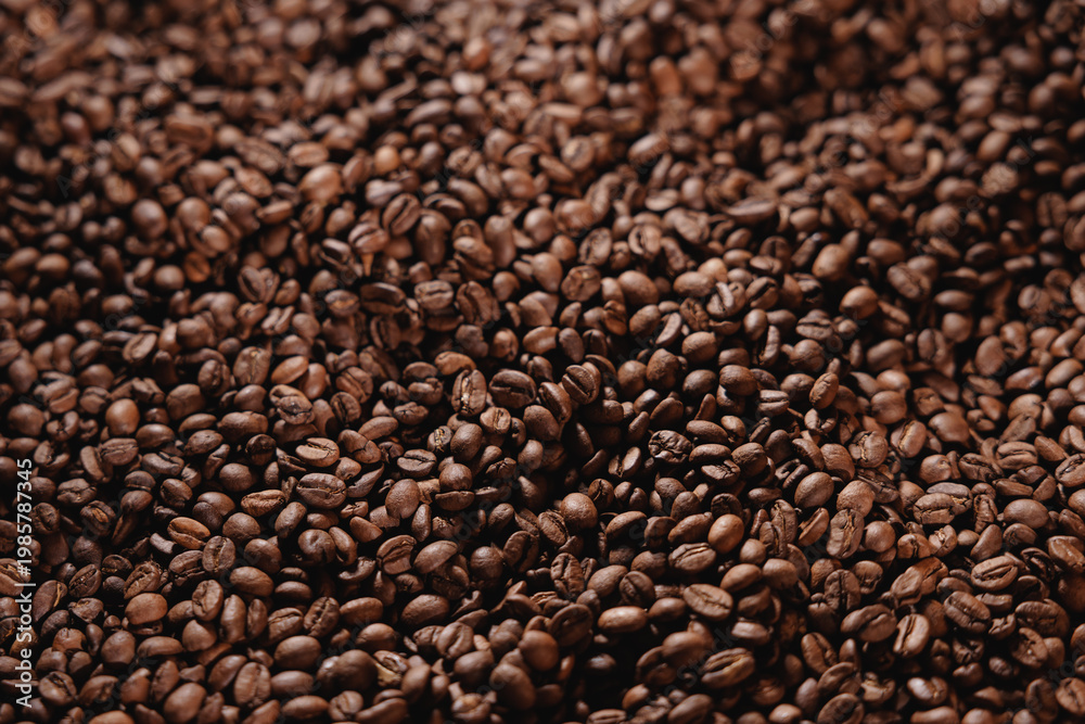 Fototapeta premium Coffee beans heaped densely in shallow focus Texture, top view