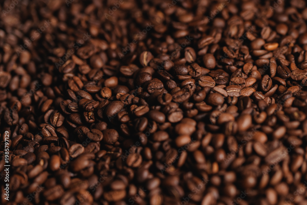 Fototapeta premium Roasted coffee beans covering tabletop surface in close view