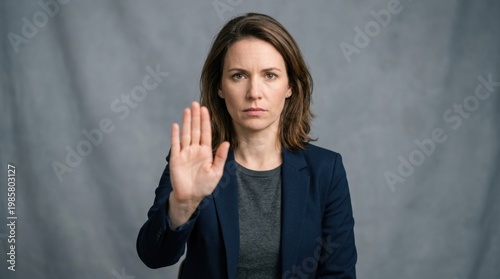 Serious young woman holding her hand up in a stop gesture, looking directly at the camera. This gesture conveys refusal, warning, or setting boundaries.