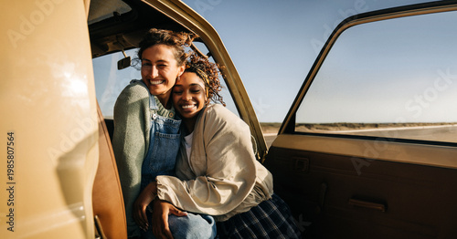 Two friends embrace inside a vintage van during a sunny road trip