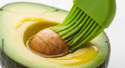 Close-up of a ripe avocado half being brushed with oil.