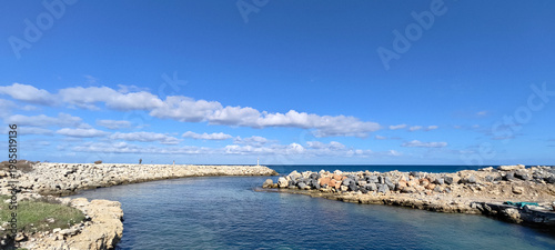 Bild auf Leinwand Panoramic view of a rocky breakwater protecting a calm coastal inlet