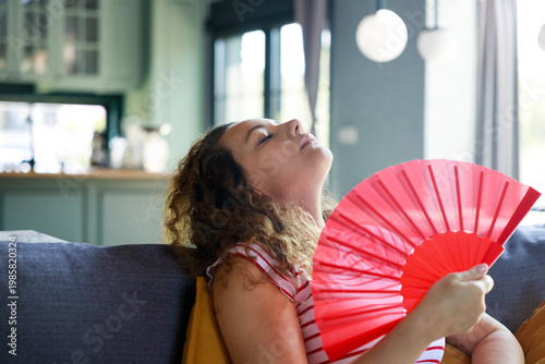 Photos Woman feeling relief using hand fan during hot weather at home