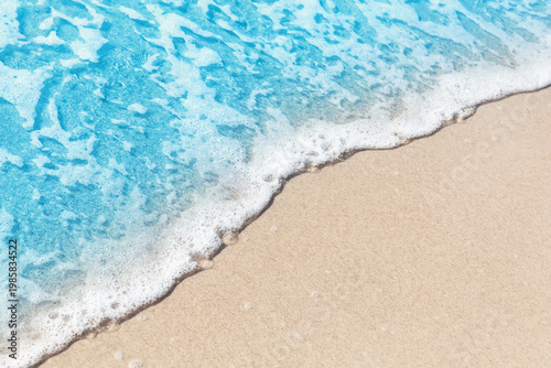 Close-up of a foamy sea wave meeting soft sand on a tropical beach. Clean and versatile background for summer, travel, resort and wellness themes.