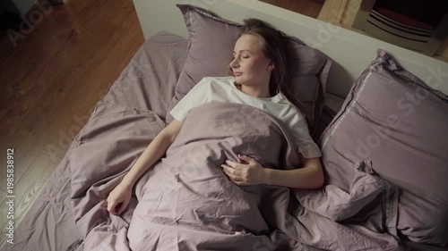 Young beautiful woman sleeping soundly in a cozy bed at home in the morning, enjoying a peaceful rest and healthy nap in her comfortable bedroom before waking up and starting the day