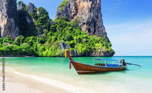 Traditional longtail boat on turquoise water at Railay Beach, Krabi, Thailand, with limestone cliffs and white sand shore.