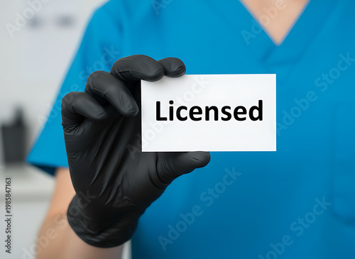 Medical professional holds Licensed card, wearing blue scrubs and black gloves. Healthcare professional shows authorization for service, confirming medical practice.  Healthcare and Professional Servi