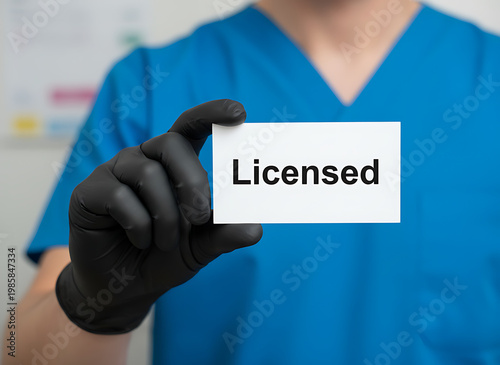 Medical professional holds Licensed card, wearing blue scrubs and black gloves. Healthcare professional shows authorization for service, confirming medical practice.  Healthcare and Professional Servi