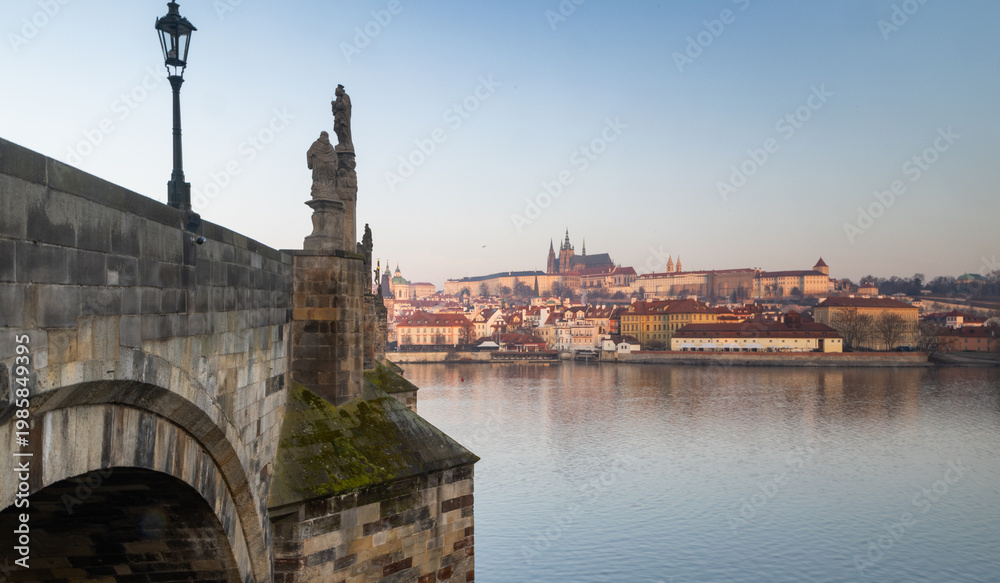 Fototapeta premium scenic view of Prague Castle and Charles Bridge glowing in golden light over the Vltava River