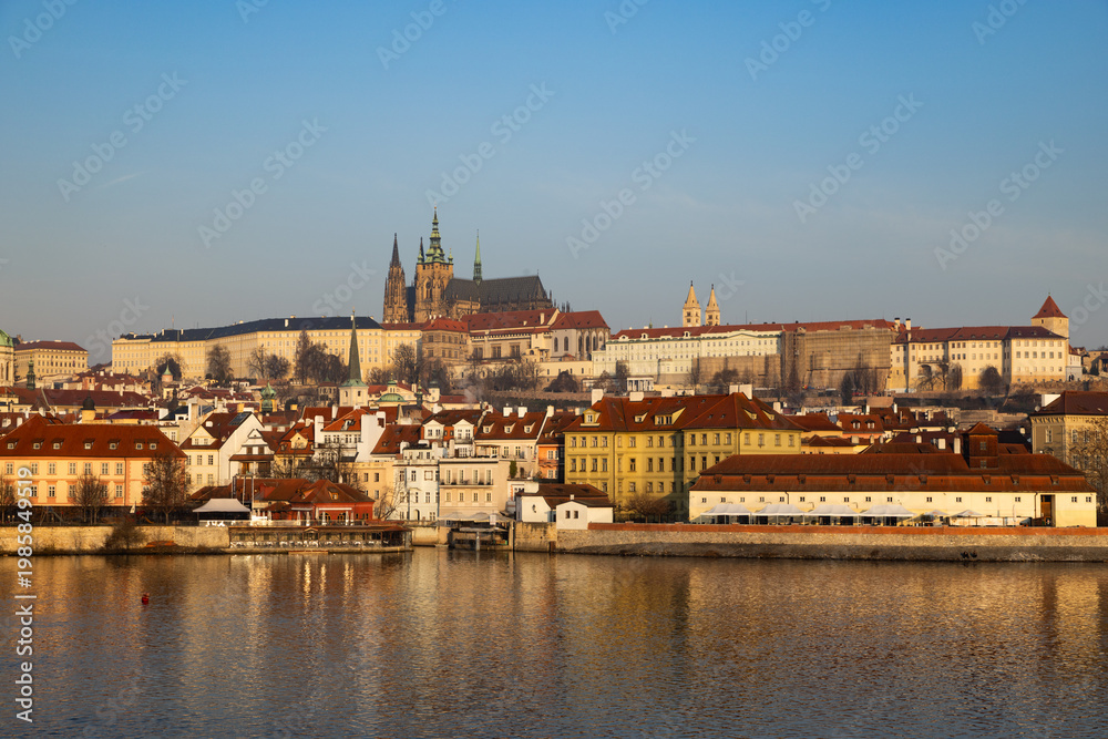 Obraz premium scenic view of Prague Castle and Charles Bridge glowing in golden light over the Vltava River
