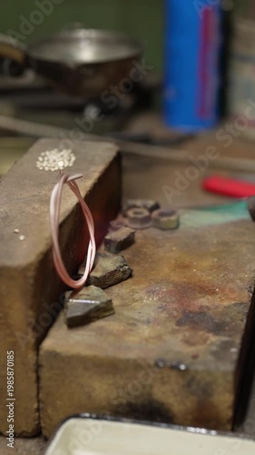 Jeweler crafting ornate silver crown with fleur-de-lis motif and detailed patterns in workshop. Traditional jewelry making process in workshop environment
