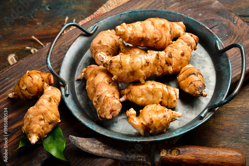 Foto Fresh organic Jerusalem artichoke in a bowl. Side view. Close-up.