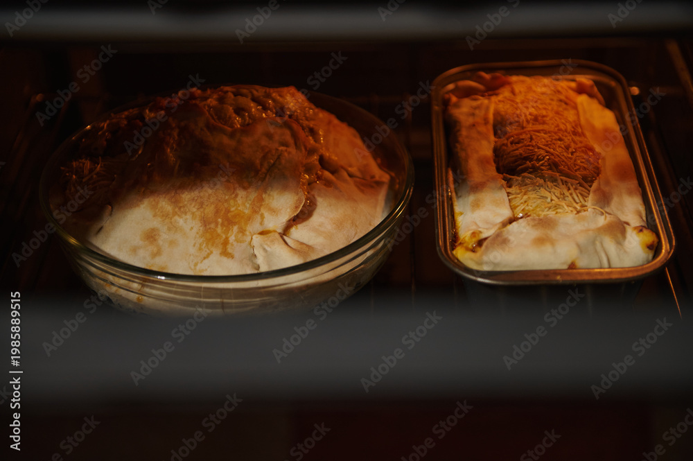 © Taras Grebinets - Homemade Pies and Loaf Baking in Oven With Golden Pastry and Melted Cheese