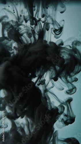Cinematic macro of black ink swirling slowly in clear water, high contrast lighting
