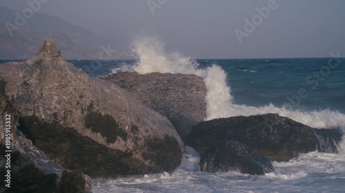 Slow motion shot of waves crushing at a rocky shore. 