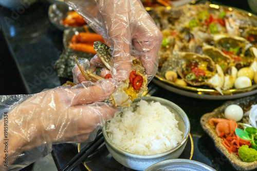 Hands preparing marinated crab with rice and garnish