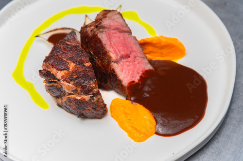 Grilled beef steak served with sauce and colorful vegetable puree on plate