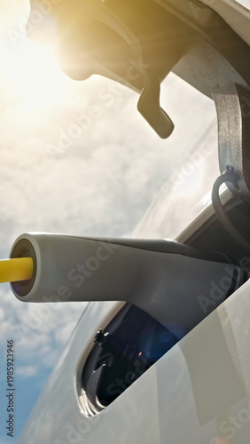 Canvas Print A sleek electric car is charged at a modern station, sunlight gleaming off its surface while a charging cable highlights renewable energy integration