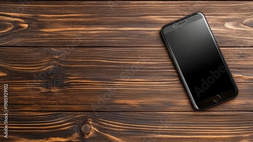 A black screen smartphone rests on a wooden table, illuminated by soft light, enhancing its modern design in a dark ambiance